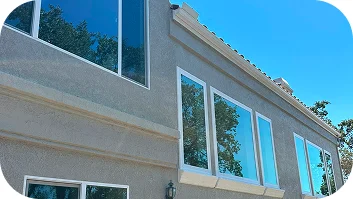 Exterior home facade with newly installed windows reflecting blue sky