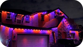 Permanent roofline light installation on residential home with colorful LED lighting at night