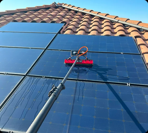 Professional solar panel cleaning service on a residential rooftop using specialized equipment